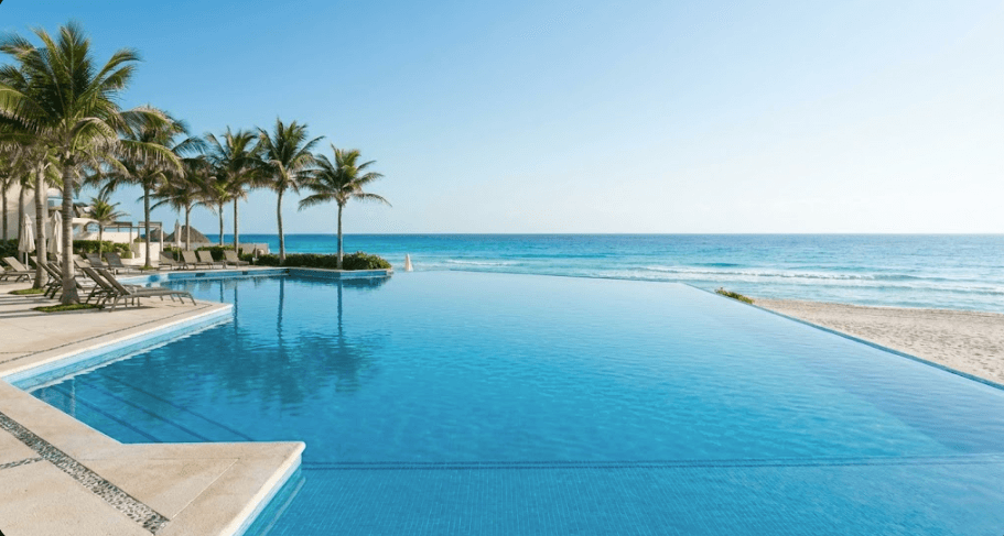 Luxury infinity pool overlooking the turquoise Caribbean sea at a Cancun resort day pass