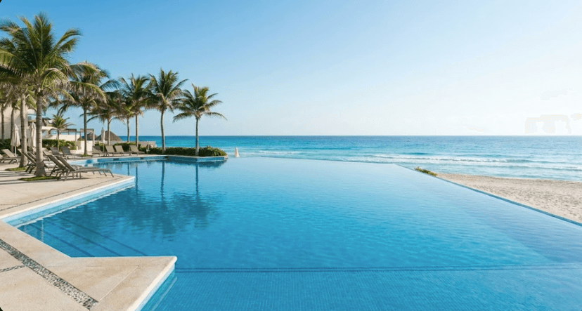 Luxury infinity pool overlooking the turquoise Caribbean sea at a Cancun resort day pass